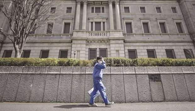 A pedestrian wearing a protective mask walks past the Bank of Japan headquarters in Tokyo.