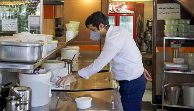 A restaurant employee, wearing a protective face mask, waits for customers in Tehran.