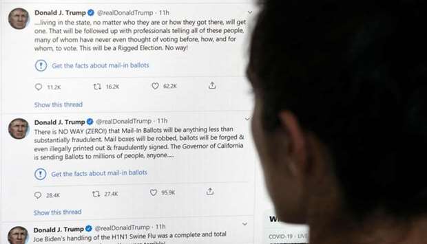 This illustration photo shows an editor in Los Angeles looking at the official Twitter account of US President Donald Trump on May 26, 2020, with two tweets by the president under which Twitter posted a link reading ,Get the facts about mail-in ballots,