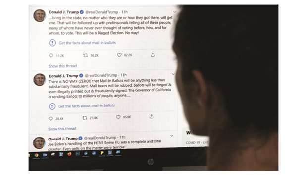 This illustration photo shows an editor in Los Angeles looking at the Trumpu2019s official Twitter account, with two tweets by the president under which Twitter posted a link reading u2018Get the facts about mail-in ballotsu2019.