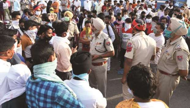 Police personnel listen to migrant workers after they blocked the national highway during a protest against the Punjab government demanding an early return to their hometowns on the outskirts of Amritsar yesterday.