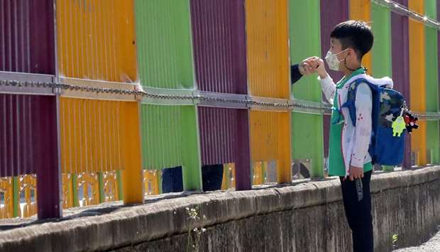 A boy holds his motheru2019s hands as he arrives at an elementary school amid the coronavirus disease outbreak in Gwangju, South Korea, yesterday.