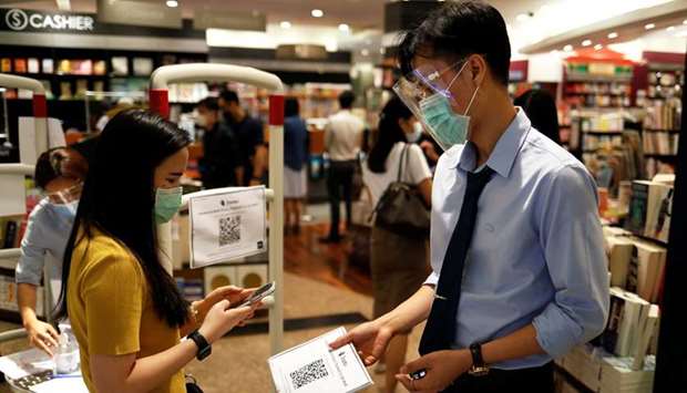 A woman wearing a protective mask scans a tracking system entering a bookstore inside a shopping mall, after the Thai government eased isolation measures, amid the coronavirus disease (Covid-19) outbreak, in Bangkok yesterday.