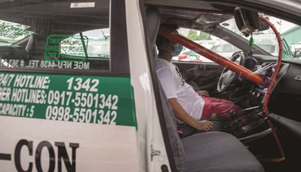 A worker sits inside a taxi with a makeshift barricade for protection against coronavirus disease (Covid-19) as taxi operations resume next week, in Quezon City, Metro Manila, yesterday.