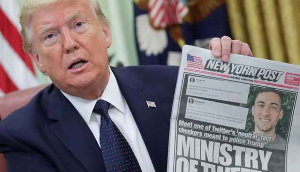 Trump holds up a front page of the New York Post as he speaks to reporters while discussing an executive order on social media companies in the Oval Office of the White House.