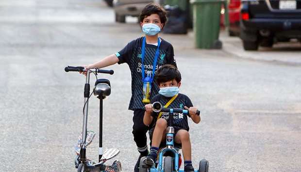 Kuwaiti children, wearing protective facemasks due to the coronavirus pandemic, cycle in a street in the Salwa district, yesterday.