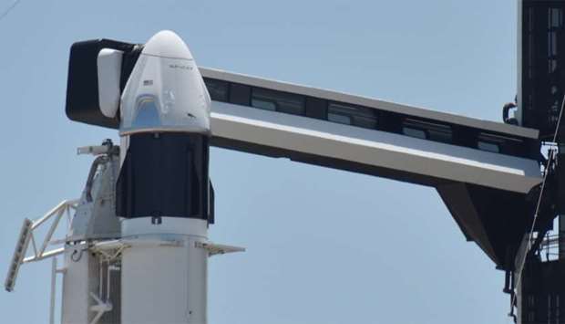 The SpaceX Crew Dragon spacecraft, atop a Falcon 9 booster rocket, is connected to the crew access a
