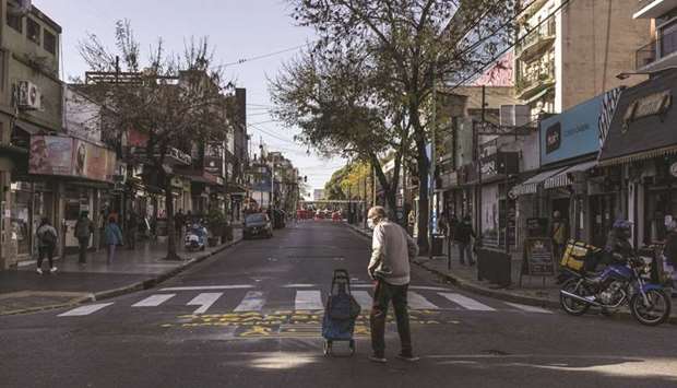 People wearing protective masks walk along a pedestrian-only street in the Belgrano neighbourhood of Buenos Aires. Argentina and its key bondholders are getting closer to a $65bn debt restructuring deal after the country defaulted on its overseas debt for the ninth time in its history.