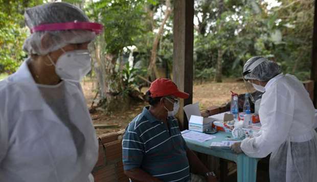 A health worker talks with a man before testing for the coronavirus disease (Covid-19), in the Bela Vista do Jaraqui, in the Conservation Unit Puranga Conquista along the Negro River banks, where Ribeirinhos (forest dwellers) live, in Manaus, Brazil, on May 29.