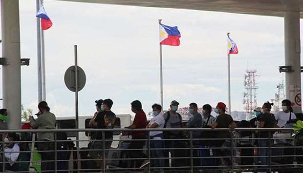 Repatriated overseas Filipino workers, who have completed their two-week quarantine as mandated by the government, stand in line at the Ninoy Aquino International Airport Terminal 2 in Pasay City.