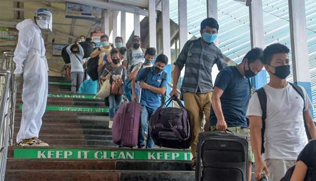 Passengers queue as they are checked by health workers upon their arrival from New Delhi at New Jalpaiguri railway station after the government eased a nationwide lockdown imposed as a preventive measure against the COVID-19 coronavirus