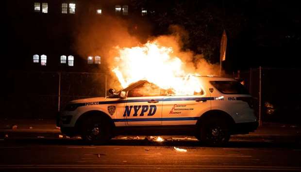 A NYPD police car is set on fire as protesters clash with police during a march against the death in Minneapolis police custody of George Floyd, in the Brooklyn borough of New York City