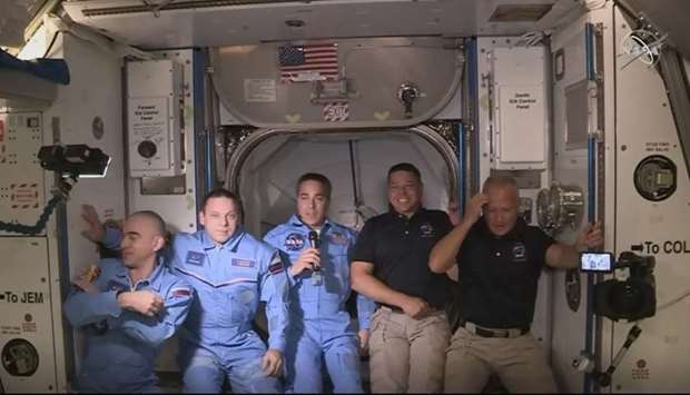 This NASA video frame grab image shows NASA SpaceXu2019s Crew Dragon astronauts Douglas Hurley(R) and Robert Behnken(2ndR) arriving after the hatch opened to the International Space Station posing with other astronauts