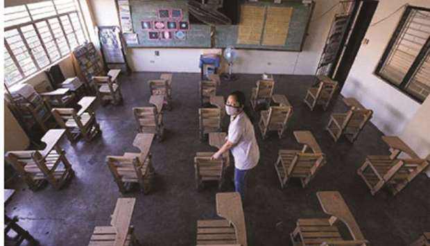 School teacher Rea Aniasco arranges chairs to meet physical distancing requirements in a classroom of the Bambang Elementary School in Pasig City.
