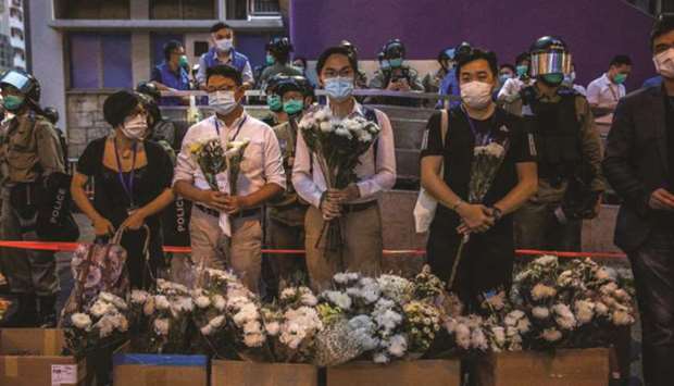 Police personnel (back) stand guard outside Prince Edward MTR underground train station as people wait to collect flowers from passersby during a vigil for protesters who were injured during police arrests on August 31, 2019.