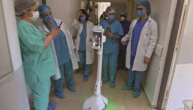 The medical staff at the Mami hospital interact with a robot, donated to the hospital, to support their efforts in combating Covid-19 pandemic, in a hallway in the hospital in the city of Ariana, north of Tunis.