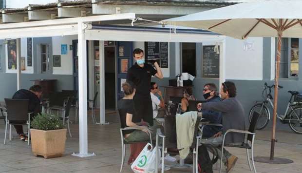 People are seen at an outdoors bar of the Balearic island of Formentera, Spain, which will begin from Monday (May 4) de-escalation stage where outdoor areas of bars and restaurants can open at half occupancy