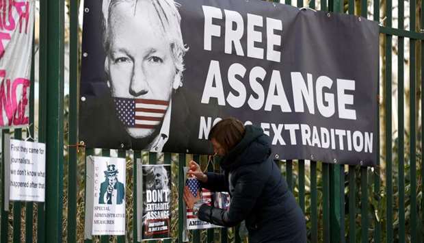 A supporter of WikiLeaks founder Julian Assange posts a sign on the Woolwich Crown Court fence, ahead of a previous hearing to decide whether Assange should be extradited to the United States, in London, Britain