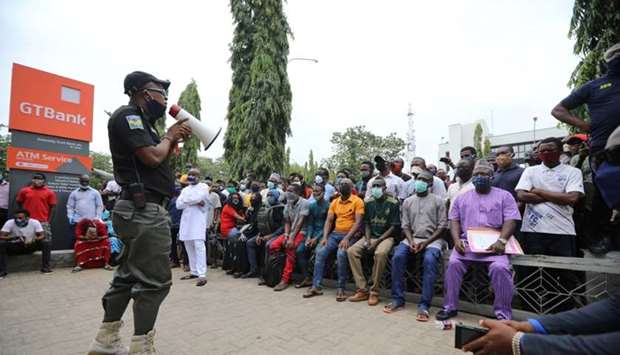 A police officer addresses the crowd at Guaranty Trust bank, as authorities ease the lockdown following the coronavirus disease outbreak, in Abuja