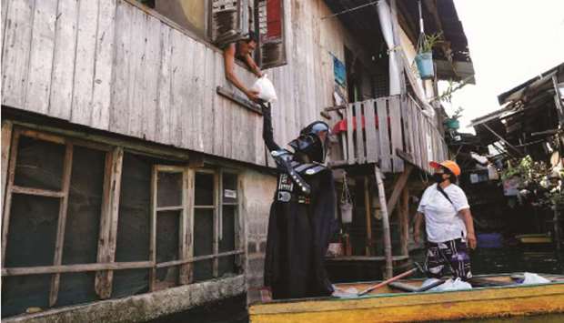 A village officer dressed as the Star Wars character Darth Vader rides a small boat to deliver relief goods to residents in the flooded Artex Compound in Malabon, Metro Manila, yesterday.