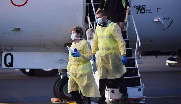 Australia biosecurity officials alight from a plane carrying the New Zealand Warriors rugby league team as they arrive in Tamworth