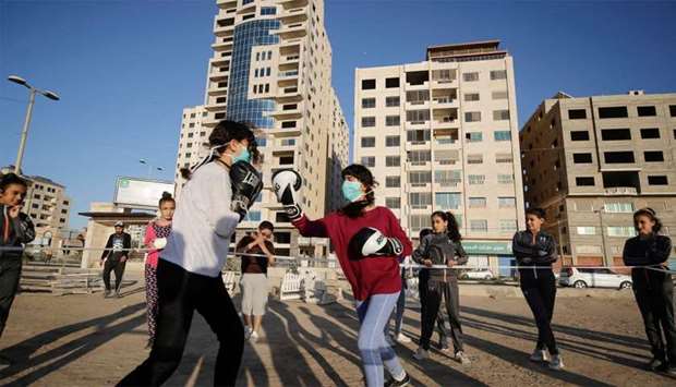 Palestinian girls clad in masks due to the COVID-19 coronavirus pandemic take part in an open-air boxing training near the beach in Gaza City