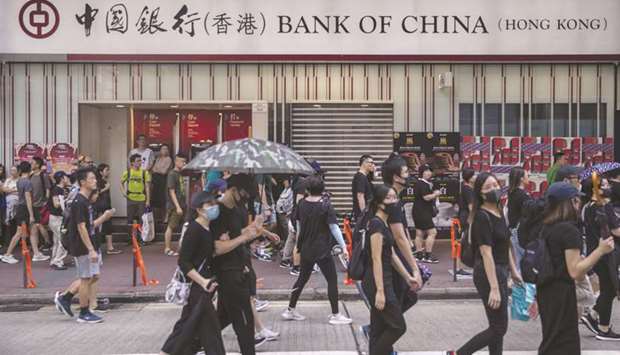 Pro-democracy demonstrators walk past a Bank of China branch during a protest in the Mong Kok district of Hong Kong. Chinau2019s fourth-largest bank by market value dropped a claim to seek additional payments from clients to cover losses from its settlement of an investment product at a price below zero, mirroring a collapse in an oil futures contract, according to four retail investors who received phone calls from the lender this week.