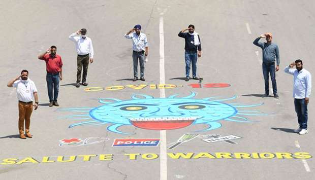 Members of National Human Rights and Crime Control Organisation pose as they stand behind a painting depicting the Covid-19 as they show gratitude to doctors, police personnel, sanitation workers and media people for their services in Amritsar yesterday.