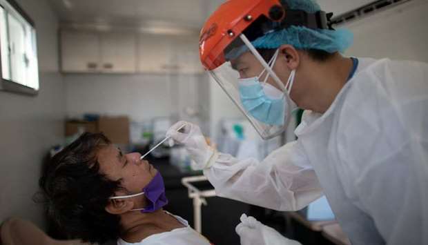 A nurse gets a swab from a man under observation for coronavirus disease (COVID-19) in a booth set up in a hospital parking lot in Manila