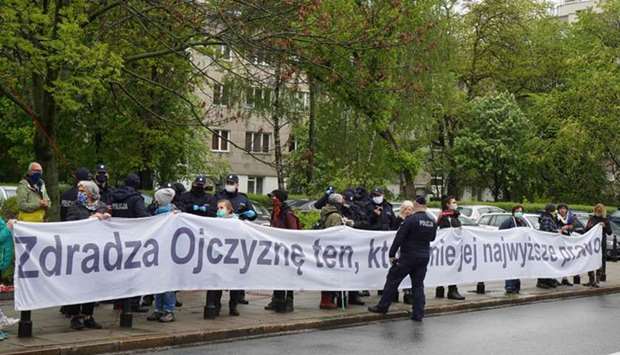 Police officers check the documents of people holding a banner which reads u2018Betrays homeland, who breaks her highest lawu2019 at a rally yesterday in front of the parliament in  Warsaw, during the parliamentary session determining the shape of the upcoming presidential election.