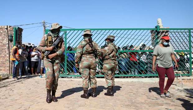 Military officers stand guard during food distribution, as South Africa starts to relax some aspects of a stringent nationwide coronavirus disease (Covid-19) lockdown, in Diepsloot near Johannesburg, South Africa