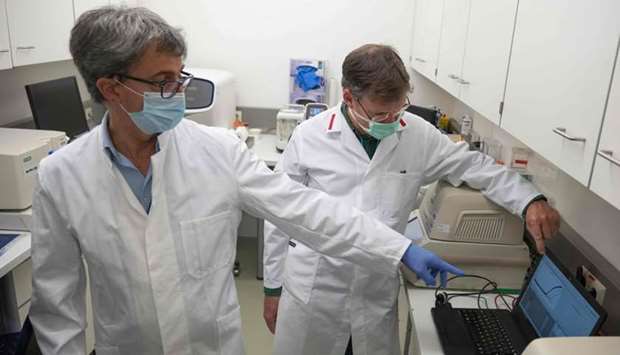 Giovanni Cattoli (L), head of the joint FAO/IAEA Animal Production and Health Laboratory, and molecular biologist William Dundon look at final results shown in the amplification plot that tell whether a person is currently infected with Covid-19 or not, at the IAEA's Laboratories in Seibersdorf, Austria, on May 7