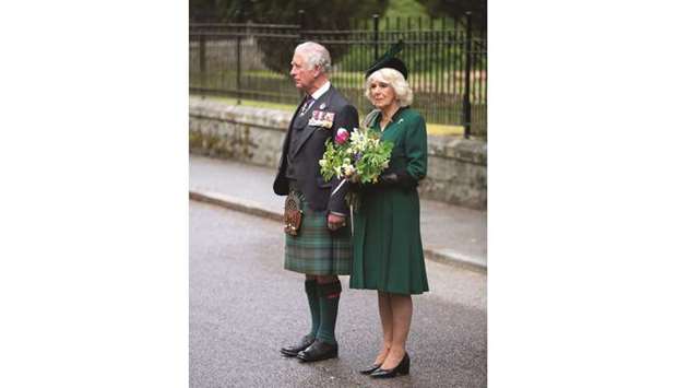 Prince Charles and his wife Camilla observe a two-minute silence to mark the 75th anniversary of VE Day at the Balmoral War Memorial, Scotland, yesterday.