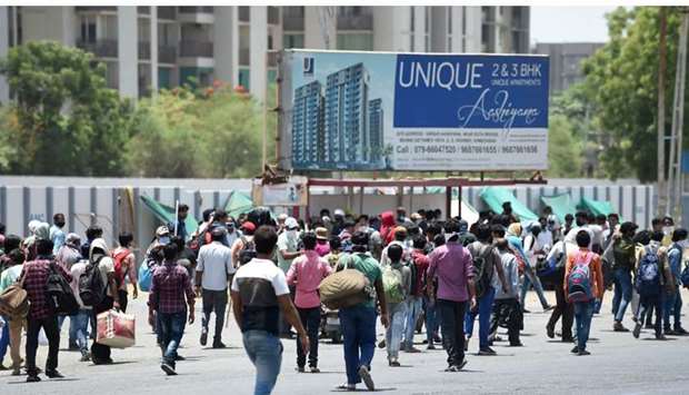 Stranded migrant workers intending to go to their hometowns, leave Gota Bridge area as Gujarat Police personnel (unseen) shoove them away during a government-imposed nationwide lockdown as a preventive measure against the spread of the Covid-19 coronavirus on the outskirts of Ahmedabad