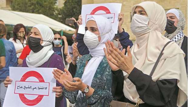 Women carry signs as they demonstrate to express solidarity with the Palestinian people near the Israeli embassy in Amman yesterday. The sign reads: u201cSave the Sheikh Jarrah neighbourhoodu201d.
