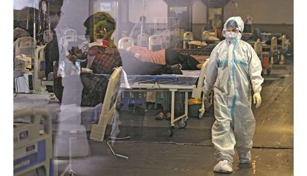 A health worker wearing a protective gear walks past Covid-19 patients inside a banquet hall temporarily converted into a Covid care centre in New Delhi yesterday.