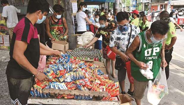This photo taken yesterday shows residents (right) collecting free food packets from a food bank called a u201ccommunity pantryu201d, run by volunteers, along a road in Quezon City in suburban Manila.