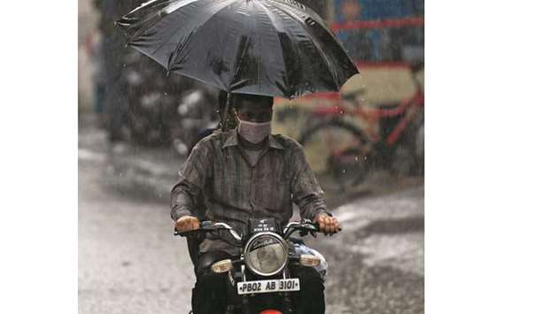 A commuter makes his way along a street during a rainfall in Amritsar yesterday. Indiau2019s top oil refiners are reducing processing runs and crude imports as the surging Covid-19 pandemic has cut fuel consumption, leading to higher product stockpiles at the plants, company officials told Reuters yesterday.