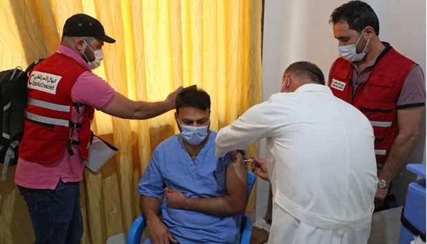 A medical worker receives a dose of the AstraZeneca Covid-19 vaccine in the presence of Qatar Red Crescent personnel at the Ibn Sina Hospital in Syria's northwestern Idlib city