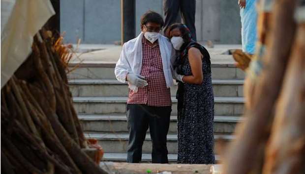 A couple mourns as they stand next to the funeral pyre of a relative who died due to the coronavirus disease, at a crematorium in New Delhi, yesterday. REUTERS