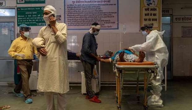 A man speaks on the phone as a doctor tries to revive his wife inside an emergency ward of a government-run hospital in Bijnor district, Uttar Pradesh