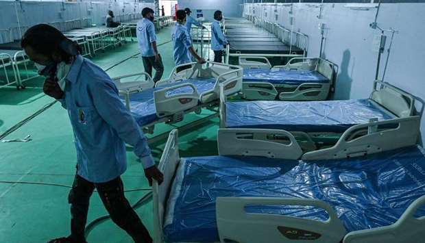 Volunteers arrange beds for patients at the Ramleela Maidan ground temporarily converted into a Covid-19 coronavirus care centre, in New Delhi