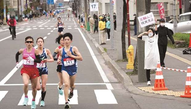 A spectator raises a paper sign reading u2018It is impossible to hold the Olympics, face up to realityu2019 along the race route during the half-marathon as part of Hokkaido-Sapporo Marathon Festival 2021, a testing event for the Tokyo 2020 Olympics marathon race.