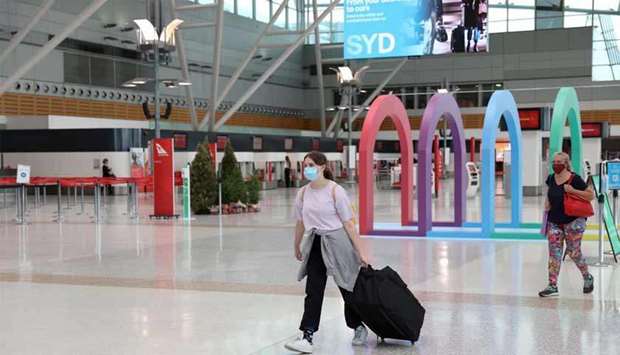 People wearing masks walk through a mostly empty domestic terminal at Sydney Airport in Sydney, Australia