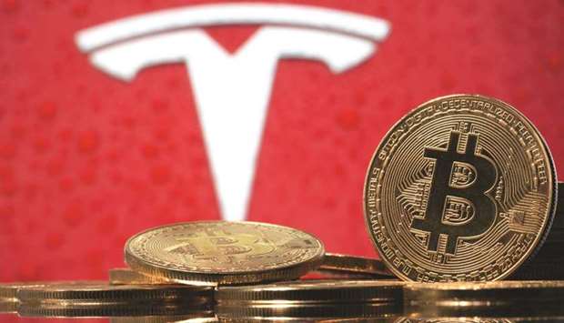 Representations of virtual currency Bitcoin are seen in front of Tesla logo.