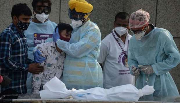 A volunteer (4L) comforts a family member of a child who died due to the Covid-19 coronavirus at a crematorium in New Delhi on May 12.