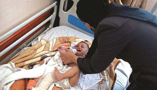 A woman feeds Palestinian infant boy Omar al-Hadidi as he lies on a hospital bed after health officials said a missile struck a house, killing his mother and four siblings, in Gaza City, yesterday.