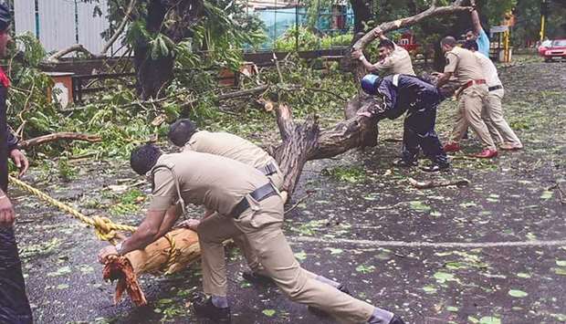 Police personnel clear fallen trees from a road following strong winds caused by the impending cyclone Tauktae at Panjim in Goa yesterday.