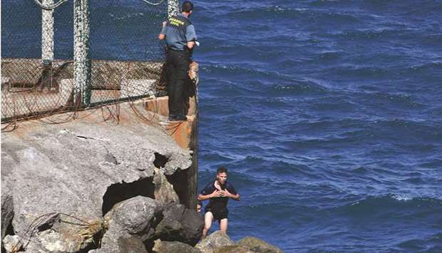 A Spanish Civil guard observes migrants who swam to the Spanish enclave of Ceuta from neighbouring Morocco.