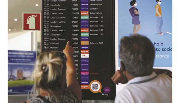 People watch a Faro Airport arrivals screen display information on the first day that Britons are allowed to enter the country without needing to quarantine, in Faro, Portugal.